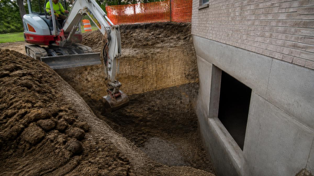 Contractor using excavation equipment to create a light well, impacting the cost of adding light wells to basement