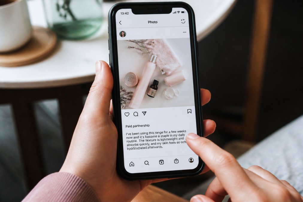 Smartphone screen displaying an Instagram post with a clear "Paid partnership" label prominently displayed at the top of the caption area, showing how the disclosure appears before any product description text