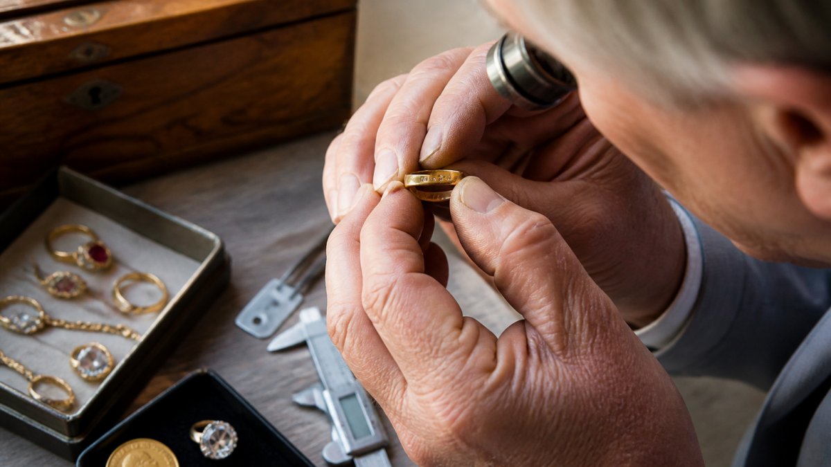 Jeweller using a loupe to examine hallmarks on an antique gold ring