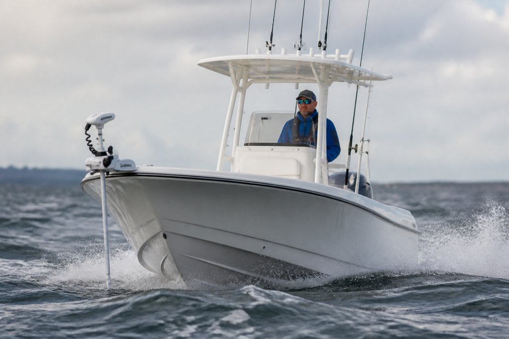 Angler steering a center console boat equipped with a 100 lb thrust trolling motor on choppy coastal waters