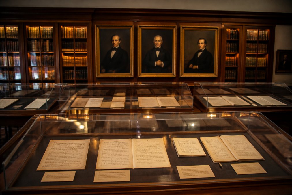 Historic archive room with period-era constitutional documents and manuscripts displayed under archival lighting, representing the Reconstruction era and the drafting of the 14th Amendment