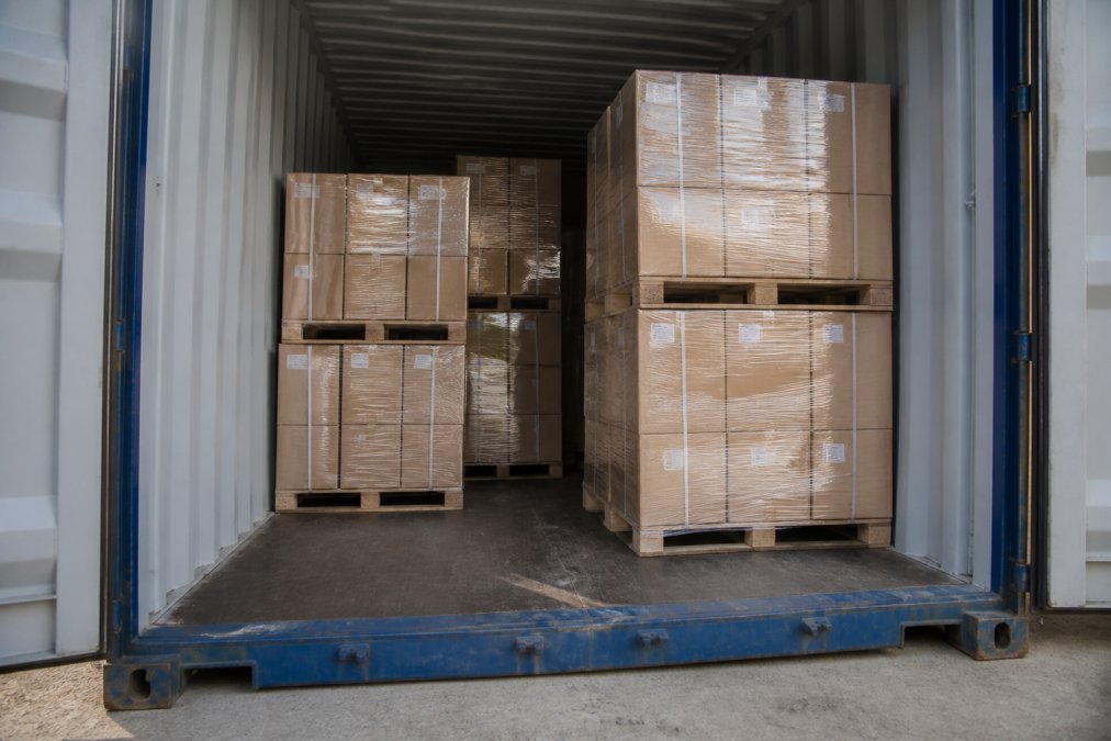 Wooden pallets and boxes stacked inside a 20-foot container dimensions space to show cargo capacity.