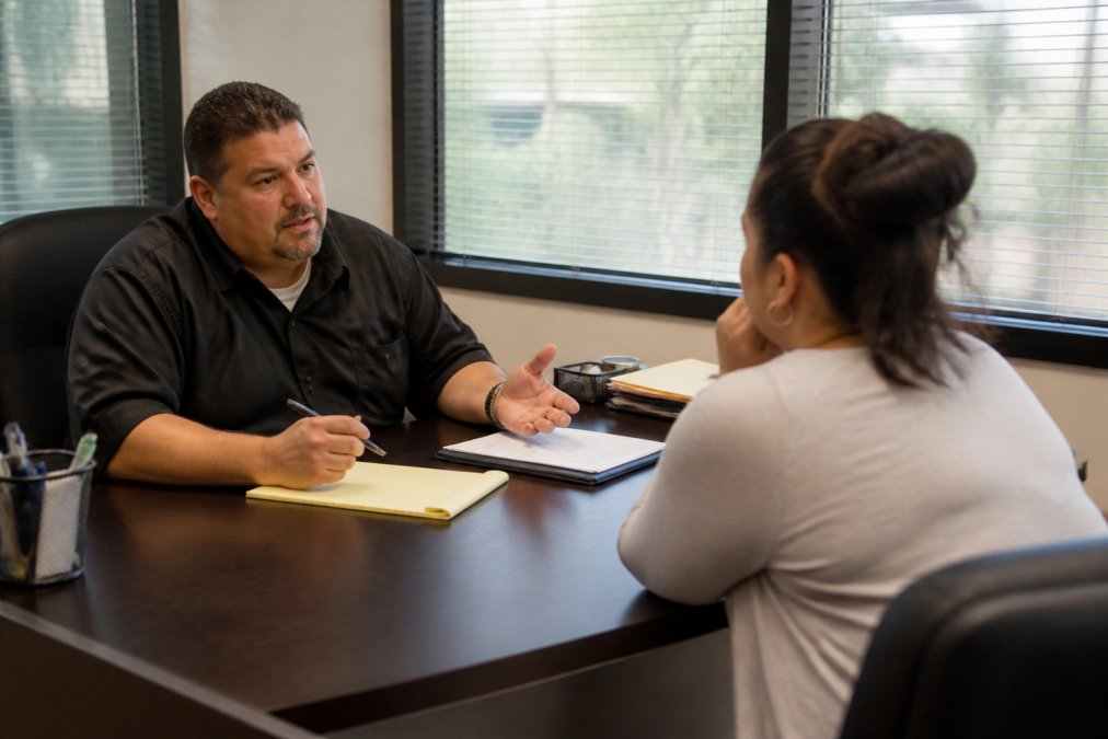 Bail bondsman explains 24 hour bail bonds to a concerned family member in a modern office setting