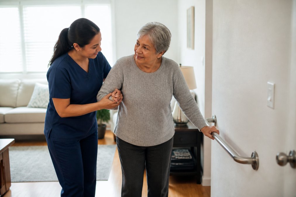 24-Hour Home Care Coordination: A Complete Guide 1 Caregiver providing mobility support to an older adult in a home set up for 24-hour home care coordination.