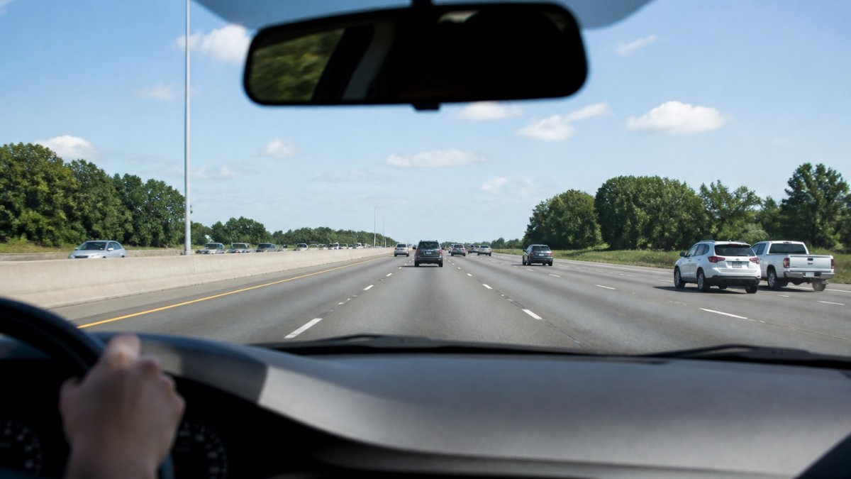A driver's view from inside a car on a multi-lane highway in Pearland, Texas, with clear green road signs and a bright blue sky, showing a typical daytime commute