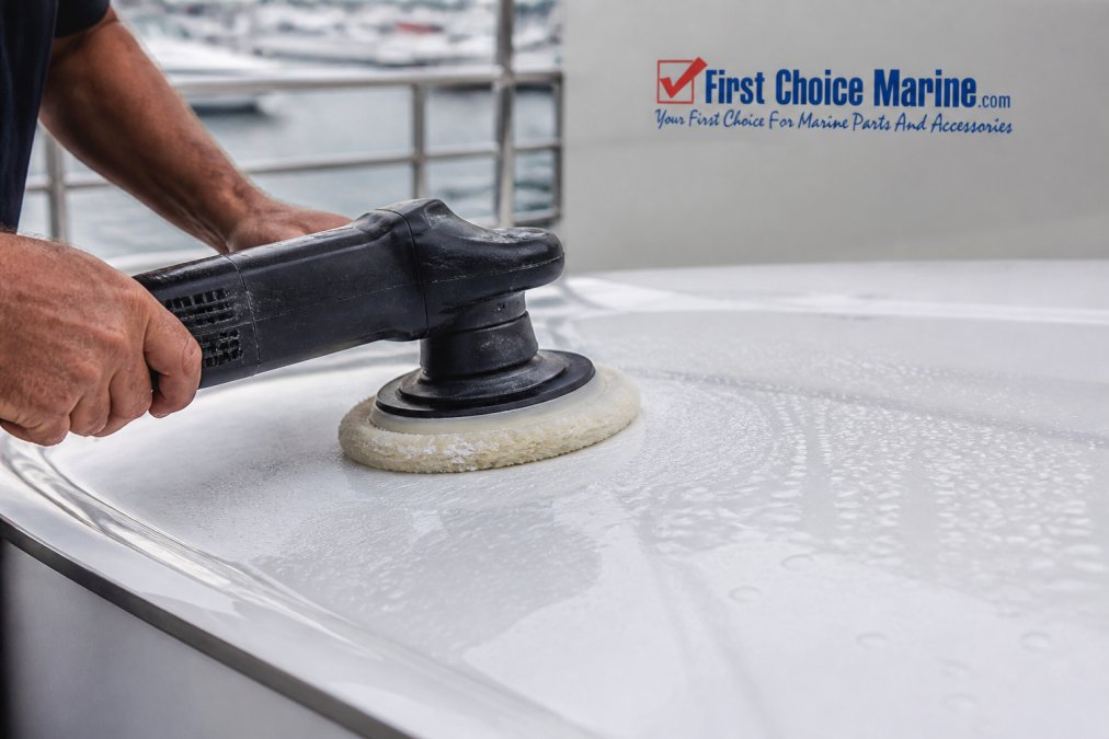 Close-up of a wool compounding pad attached to a rotary buffer polisher being applied to a glossy white fiberglass gelcoat surface, with compound residue visible and water droplets reflecting light on the marine finish