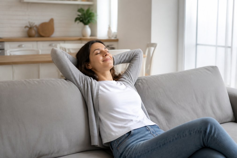 Relaxed homeowner sitting in a clean, clutter-free living room with natural light, appearing relieved and satisfied after move-in cleaning is complete