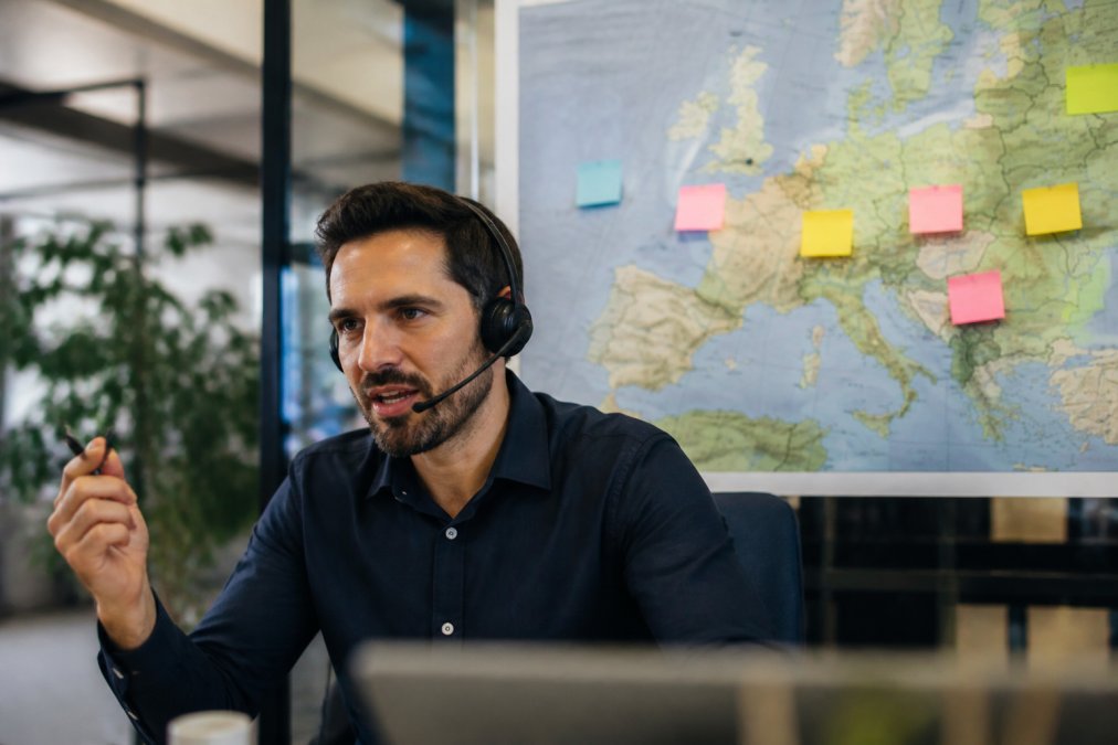 Sales professional on a call before a European map, planning international sales expansion in a modern office