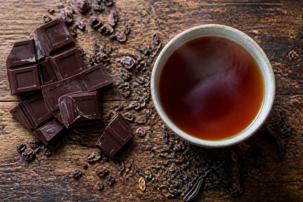 Infographic illustrating the flavor pairing process between dark chocolate and black tea on a rustic table