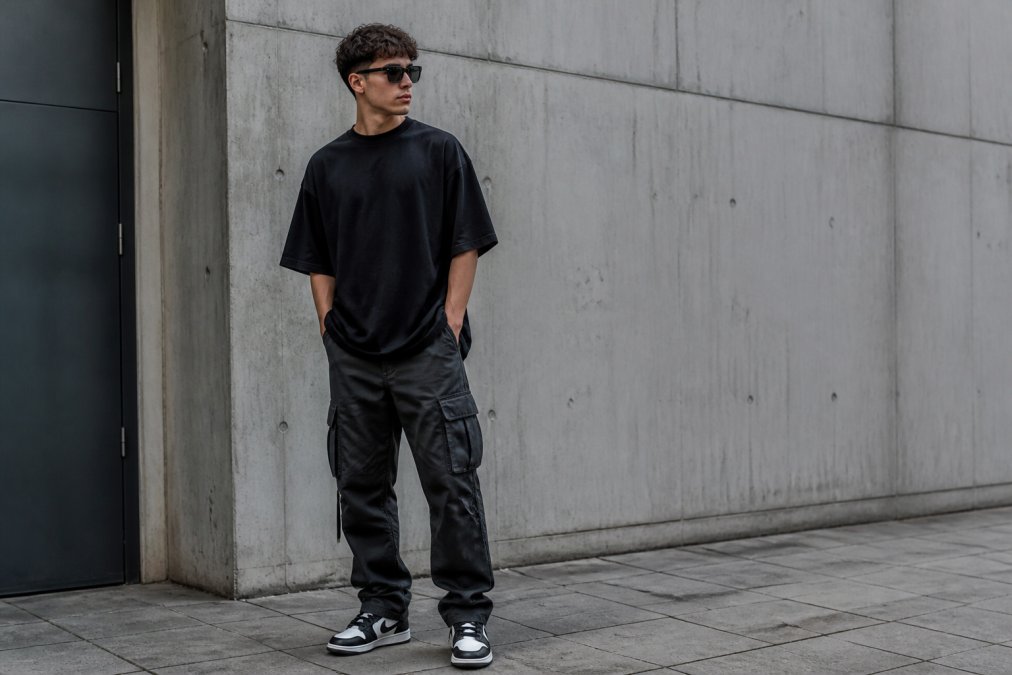 Jonge man in een oversized zwart t-shirt en cargobroek als onderdeel van de 5 beste streetwear essentials voor heren.