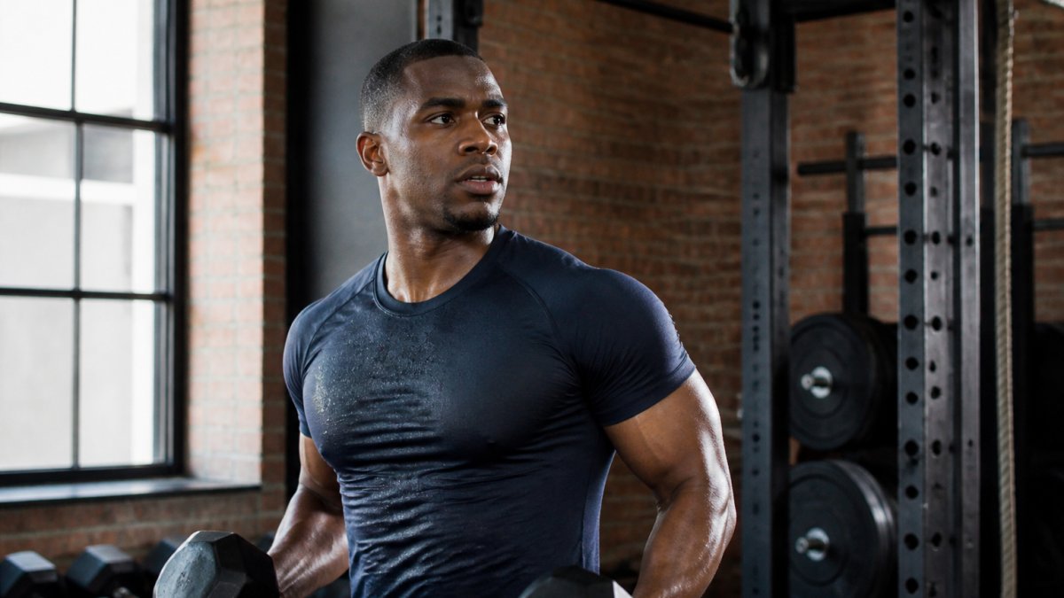 Male athlete performing a strength training workout in a fitted moisture-wicking shirt at the gym