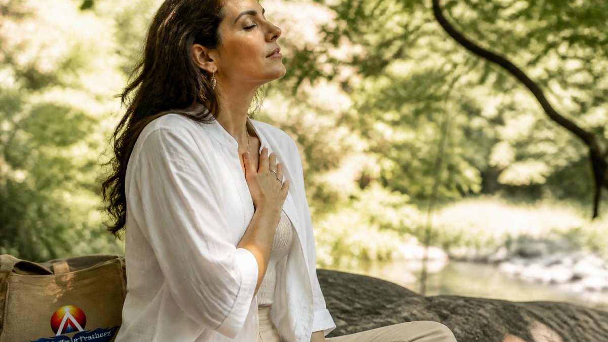 5 Signs You Need a Spiritual Consultation 1 Woman sitting peacefully outdoors in natural light, hand placed gently on heart, with a calm contemplative expression, surrounded by trees and soft dappled sunlight suggesting inner reflection and spiritual awareness