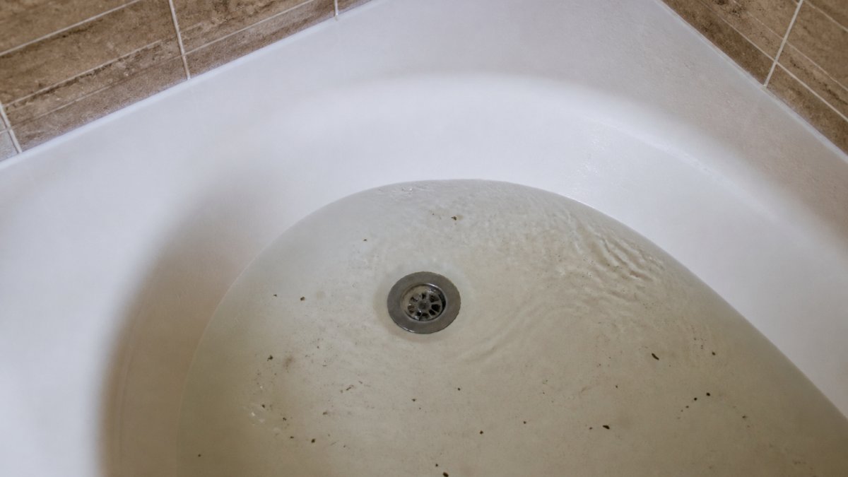 Diagram showing water pooling in a bathtub due to a clog; call a plumber drain if you see these signs.