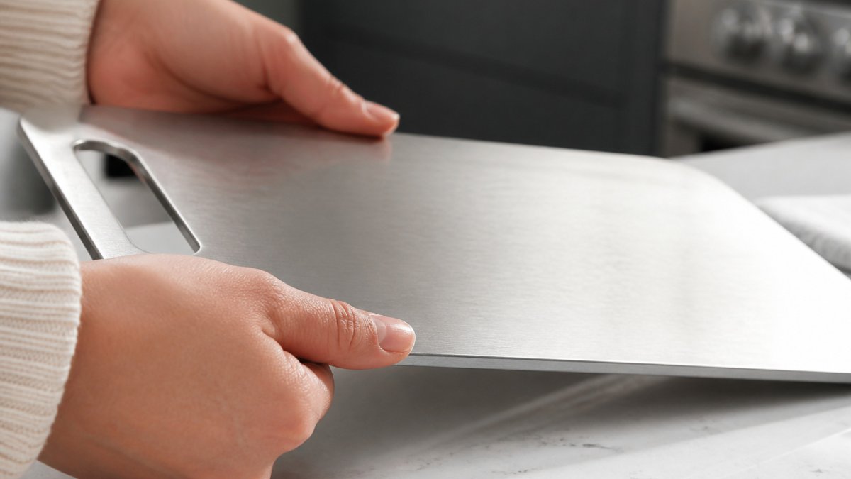 Shopper checking the brushed edge of a stainless steel cutting board on a kitchen counter