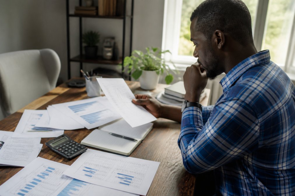Investor reviewing financial data on a laptop to predict earnings beats at a desk with notes and a calculator