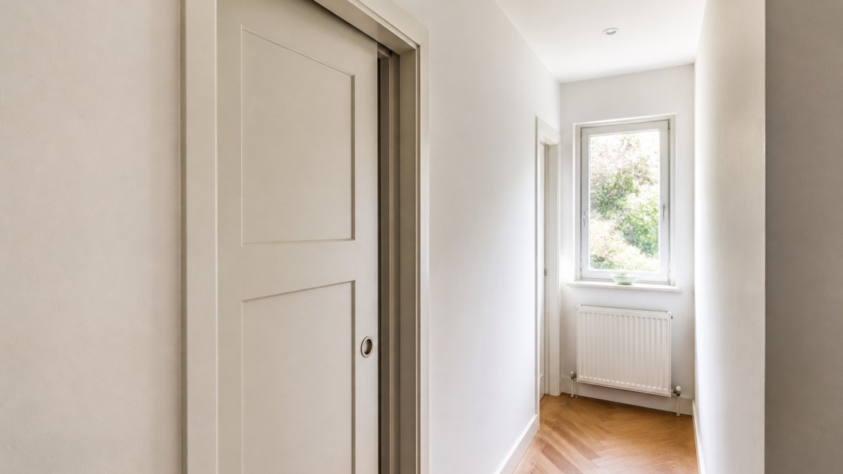 Diagram illustrating how a wall-recessed sliding door maximizes floor space in a narrow, sunlit hallway.