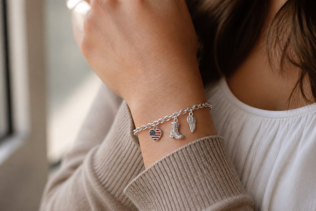 Close-up of a woman's wrist wearing a sterling silver charm bracelet with small military-themed charms, soft natural window light, shallow depth of field