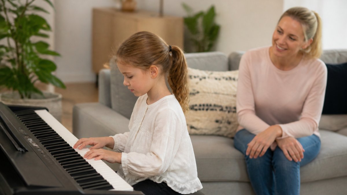 A young child playing a digital piano while a parent watches, supporting the benefits of music education for children in