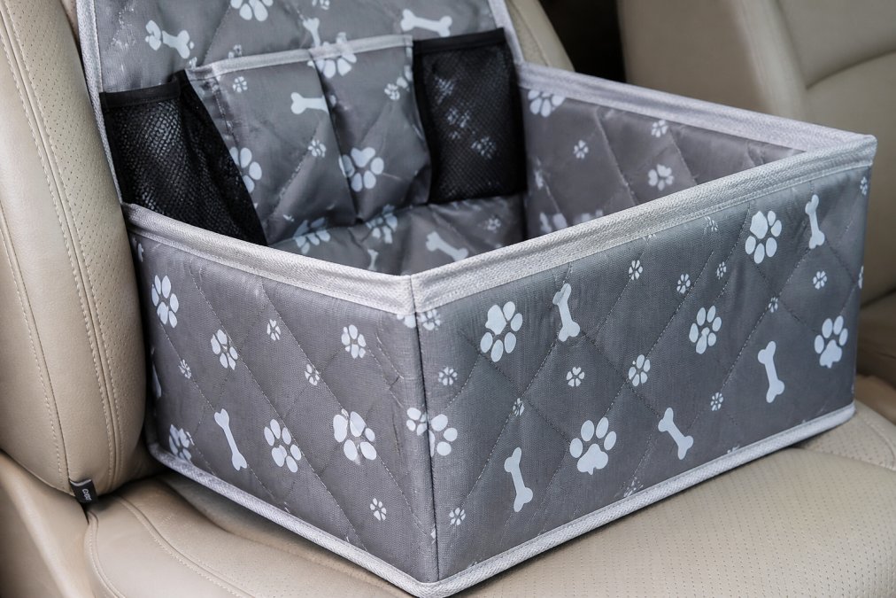 Close-up of a dog car seat cover showing reinforced stitching and scratch-resistant fabric texture with visible wear resistance, photographed in natural daylight