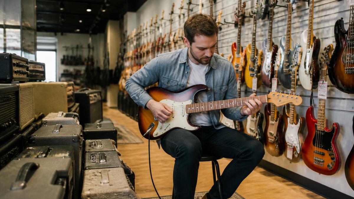 Musician testing an electric guitar in a Gold Coast shop among the best musicfactorydirect alternatives for gear.