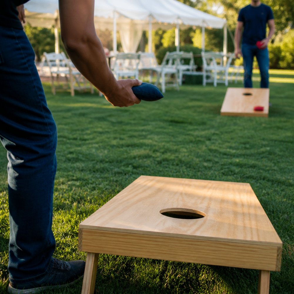 A diverse group of employees playing cornhole and giant Jenga outdoors on a sunny day, with white tents and picnic tables set up in the background