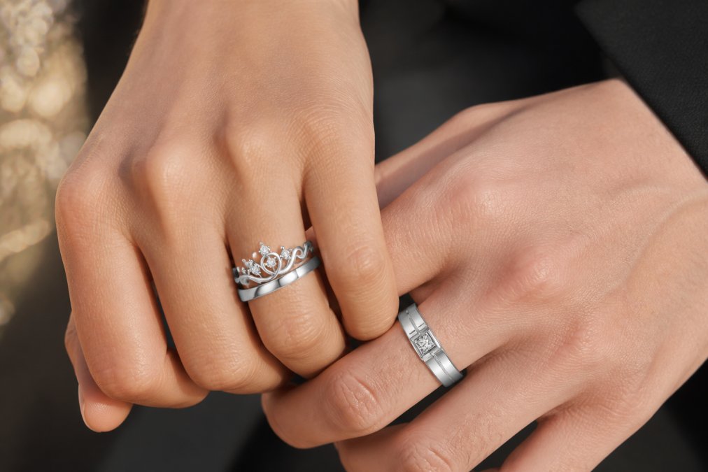Close-up of a couple's hands wearing matching sterling silver rings with zircon stones, natural sunlight highlighting the geometric prong settings and the sparkle of the stones