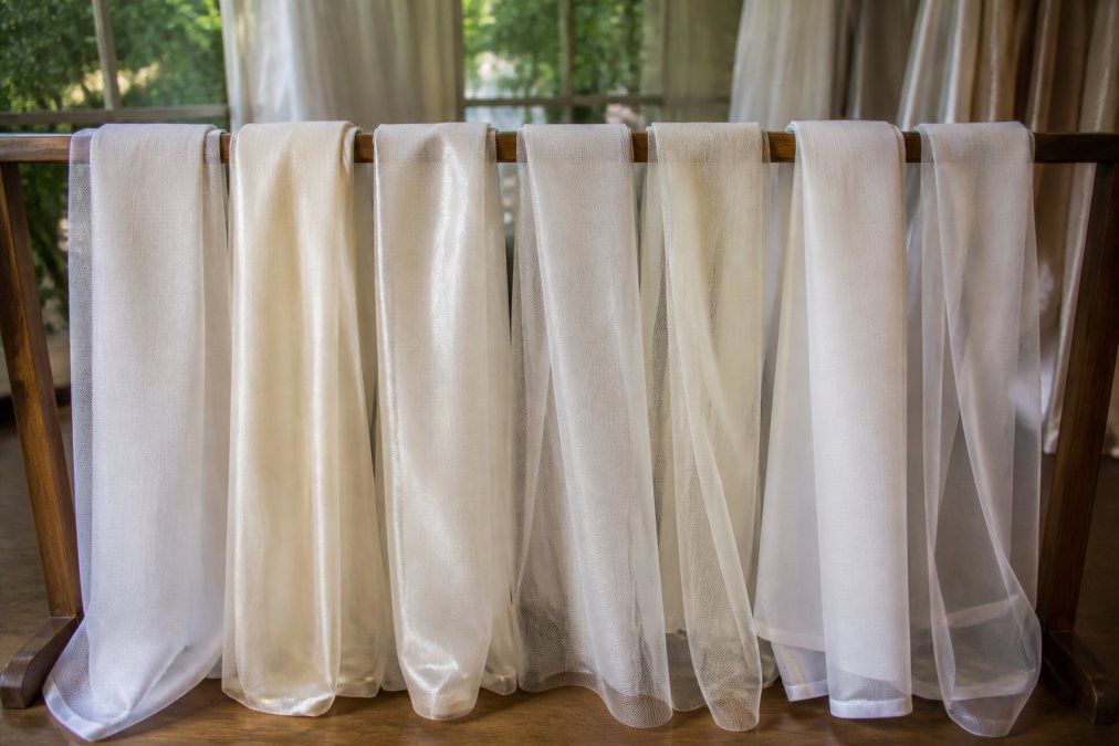 Comparison infographic of the 7 best sheer fabrics for wedding draping, featuring swatches of voile, chiffon, and organza.