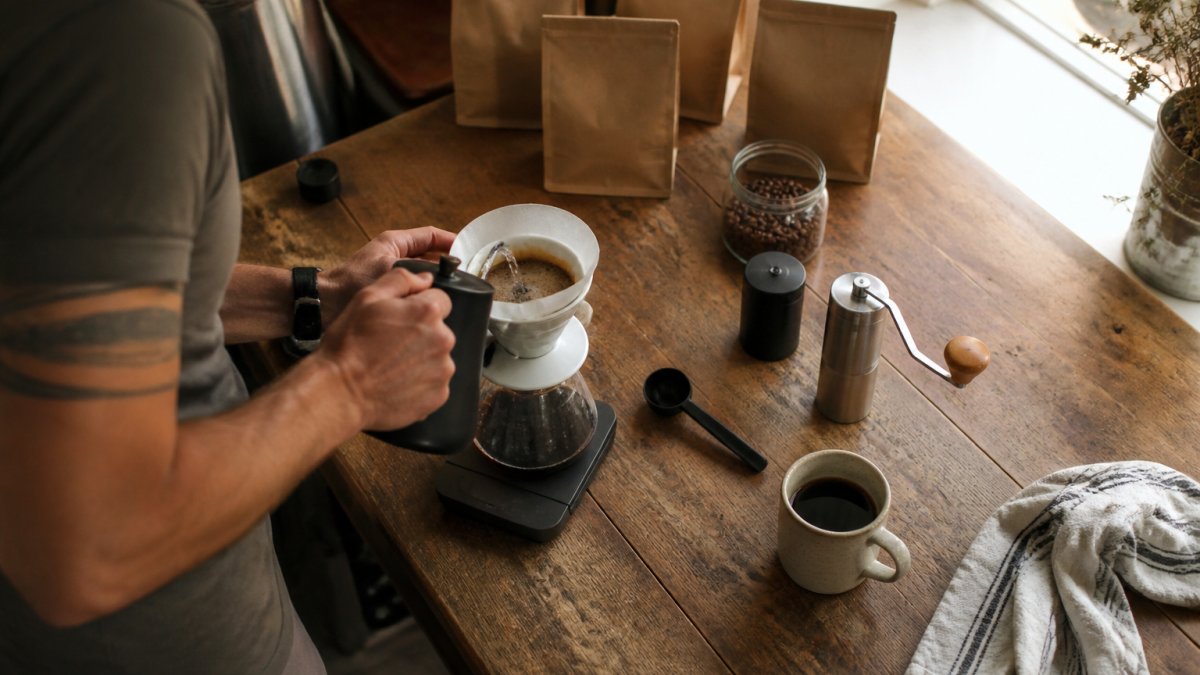 Freshly brewed cup of specialty coffee next to assorted bean bags on a sunny kitchen counter