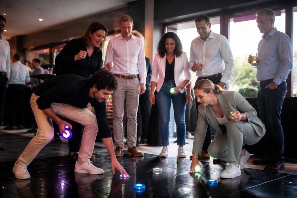 Diverse groep zakelijke medewerkers die enthousiast deelnemen aan een interactief teamspel in een moderne feestzaal, met lachende gezichten en actieve lichaamstaal, verlicht met warm professioneel licht