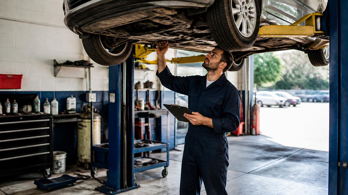 Mechanic inspecting a used car on a lift to avoid future maintenance costs