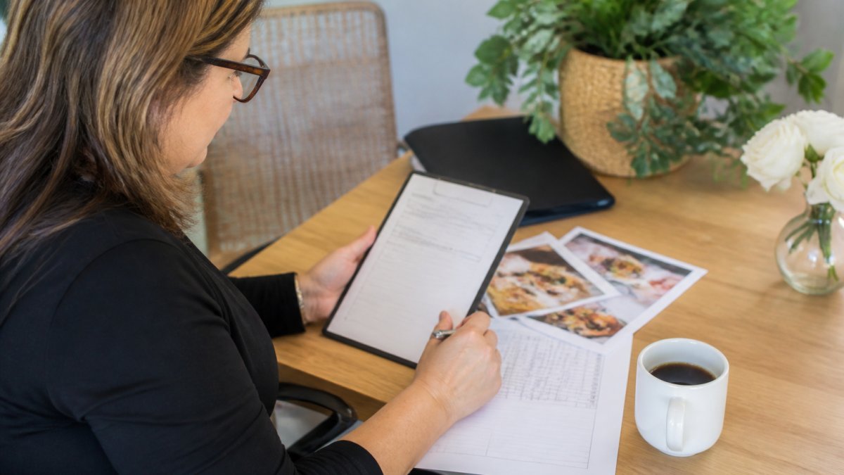 Office manager reviewing a corporate event catering checklist on a tablet and vendor form