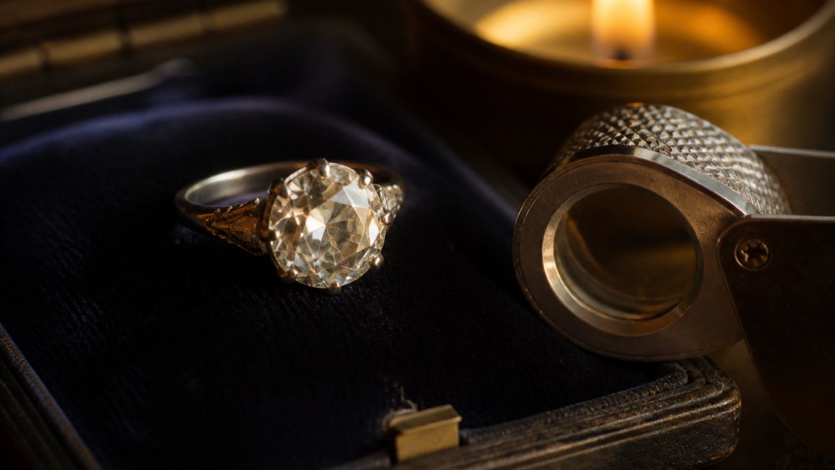 Antique old mine cut diamond ring with a jeweler's loupe on dark velvet under warm candlelight