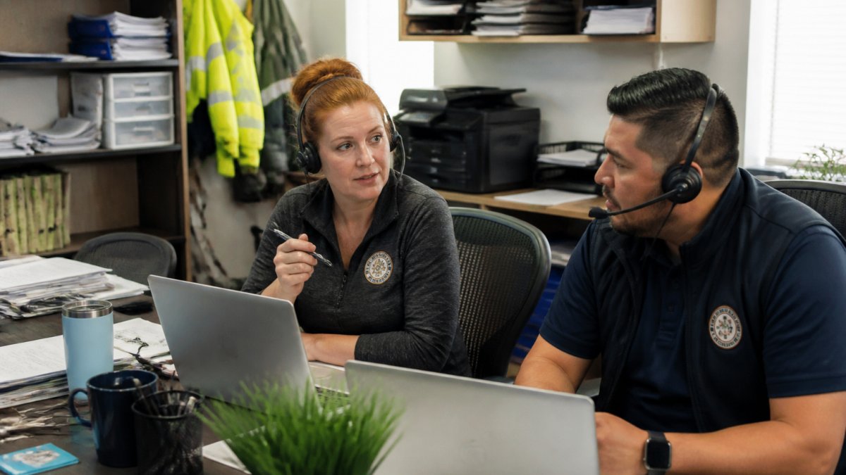 Office manager and dispatcher using secure remote collaboration tools on laptops at desks