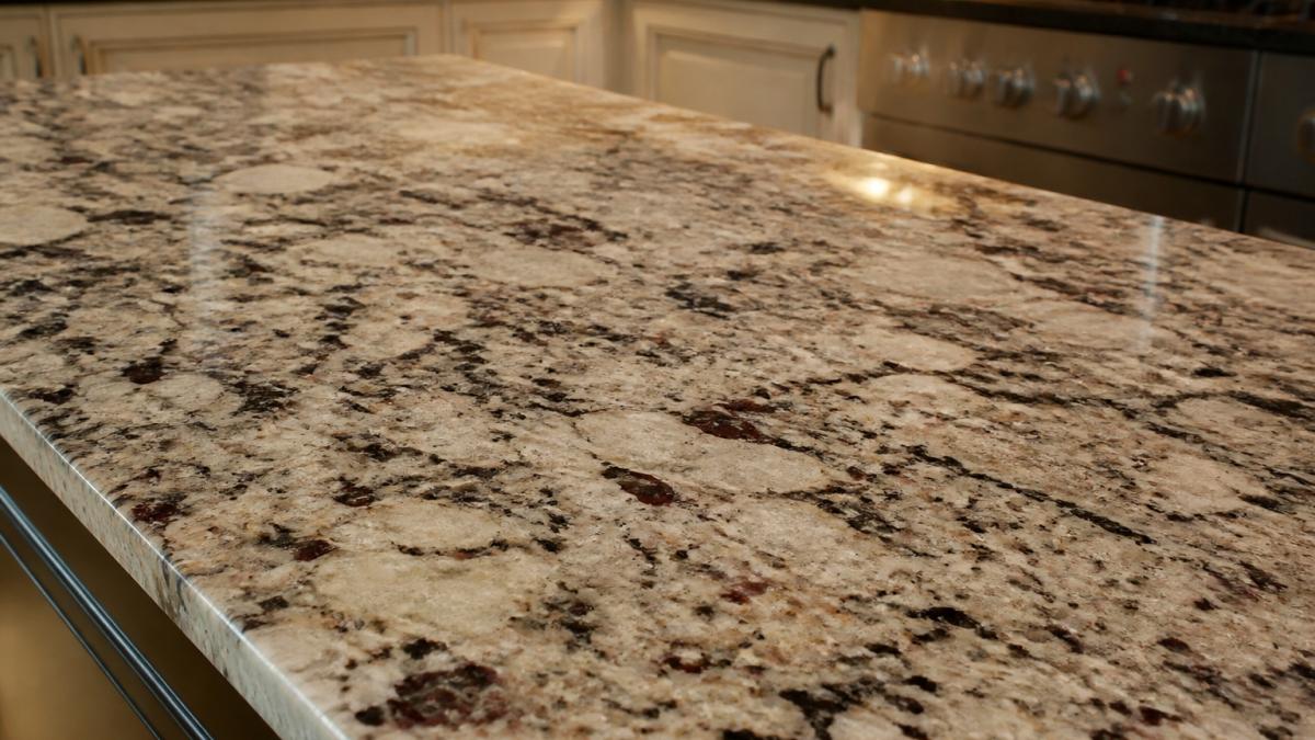 Close-up of granite kitchen worktop surface showing natural veining and speckled pattern in warm kitchen lighting