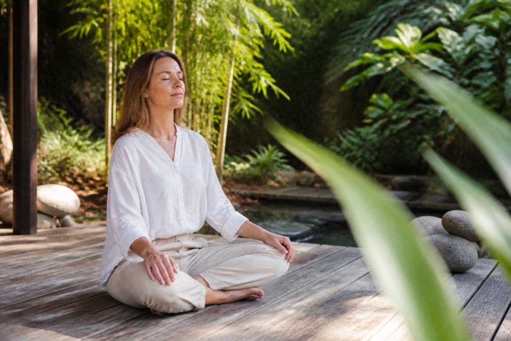 Vrouw in een rustige groene omgeving tijdens meditatie om de darmgezondheid verbeteren door diepe ontspanning en rust.