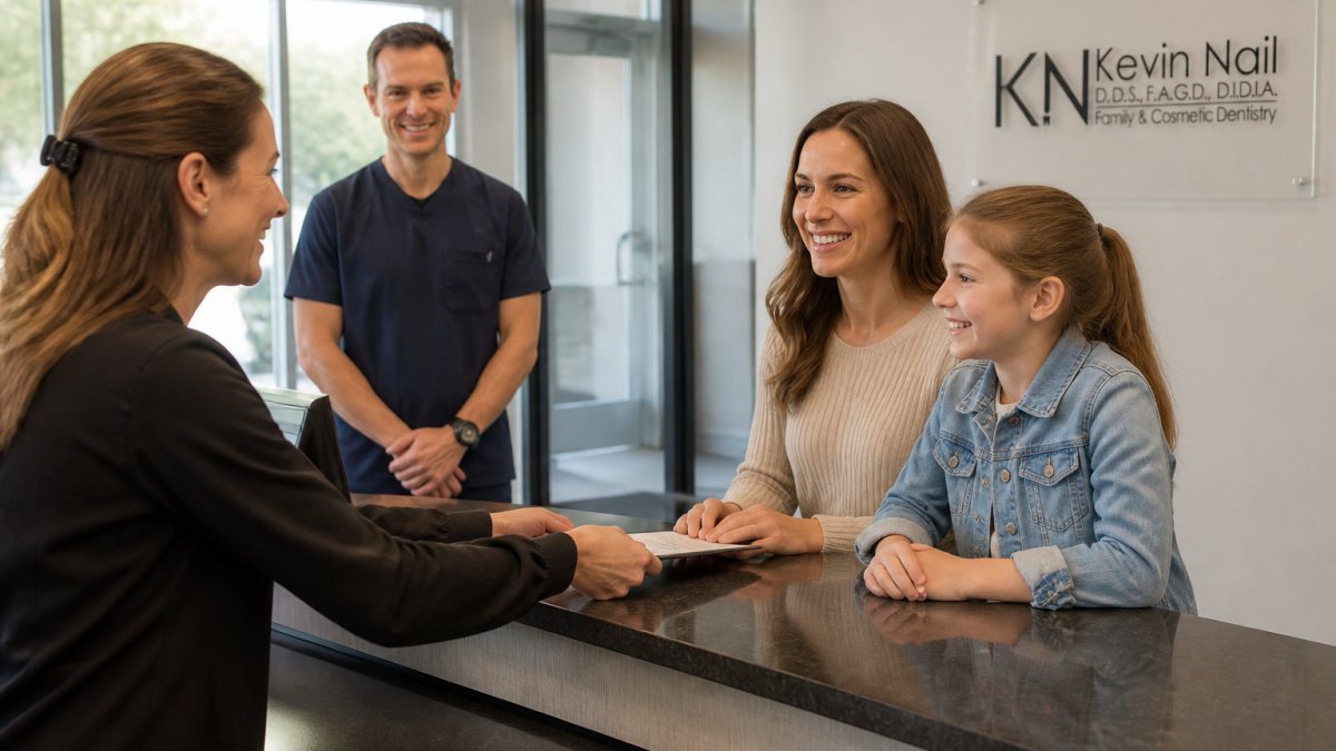 Parent and child sitting together in a modern dental office reception area, smiling and looking comfortable while dental staff greets them warmly in the background, bright natural lighting
