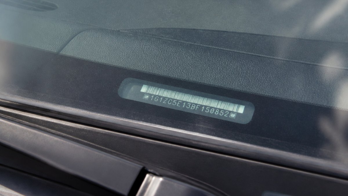Diagram showing how to locate the VIN on a dashboard to check used car history through the driver side windshield.