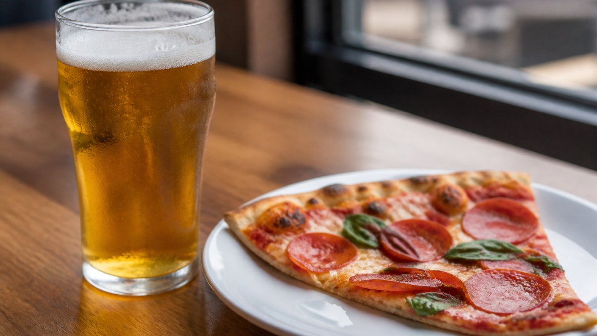 Golden lager in a glass next to pepperoni pizza to pair craft beer with pizza perfectly.