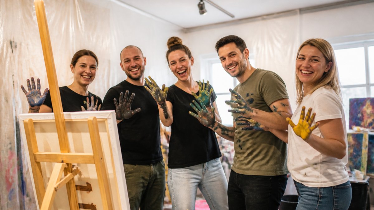 Lachende Gruppe beim kreativen Malen während eines Teambuilding Wien Events in einem hellen Workshop-Raum.