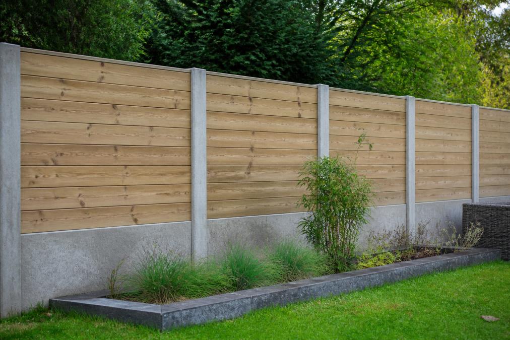 Afgewerkte hout-beton schutting in Nederlandse tuin met zichtbare betonnen palen, houten planken en natuurlijke groene achtergrond, daglichtverlicht