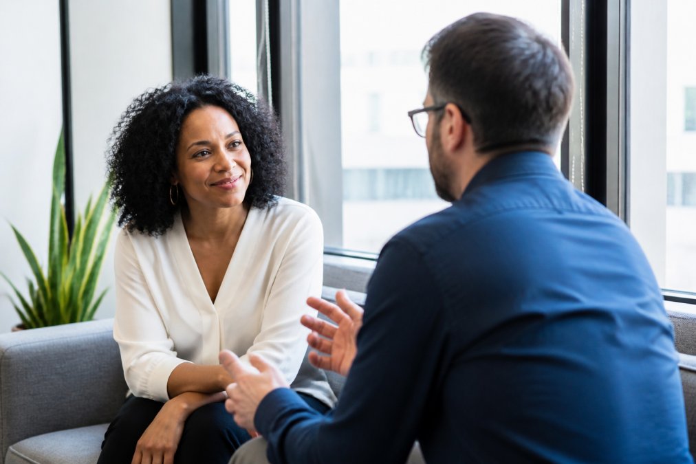 Professional manager and employee having a focused one-on-one conversation in a quiet office with natural lighting, both sitting comfortably with attentive body language and good eye contact