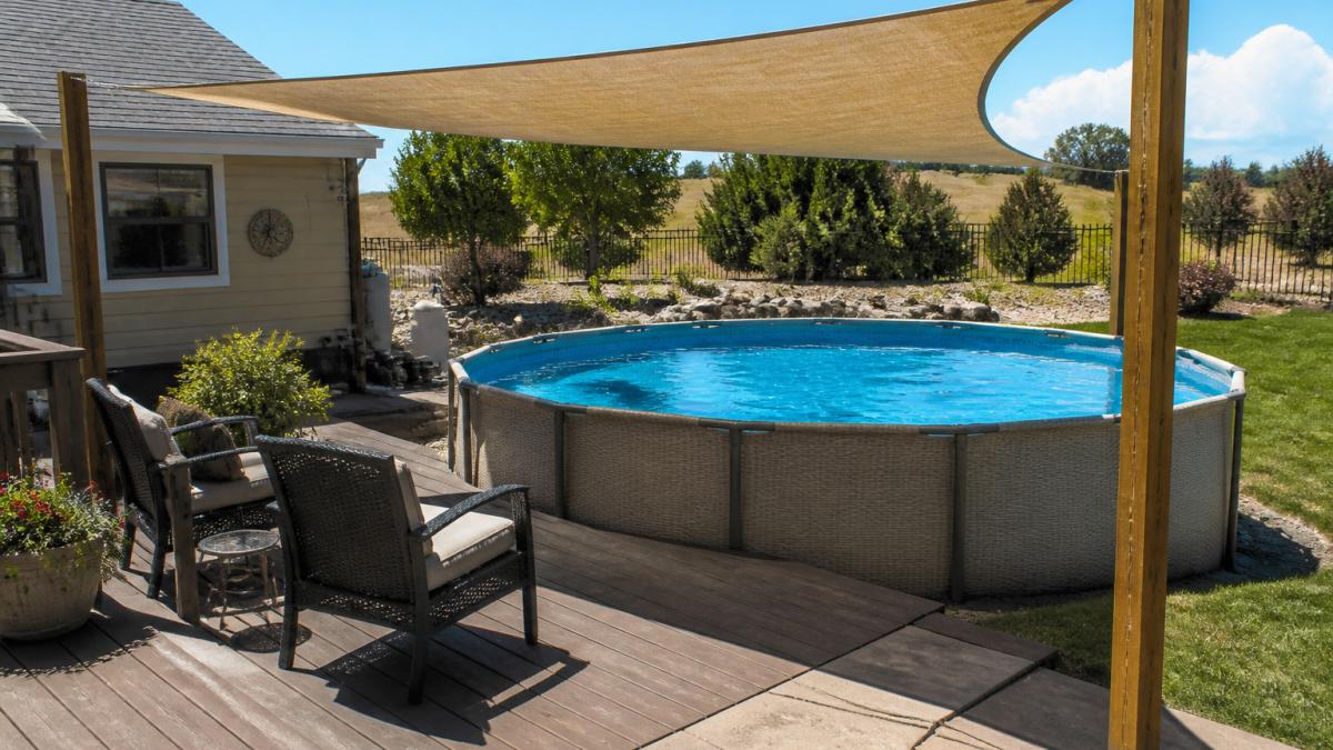 Tan shade sail over an above-ground pool to help lower pool temperature for a comfortable backyard swim.