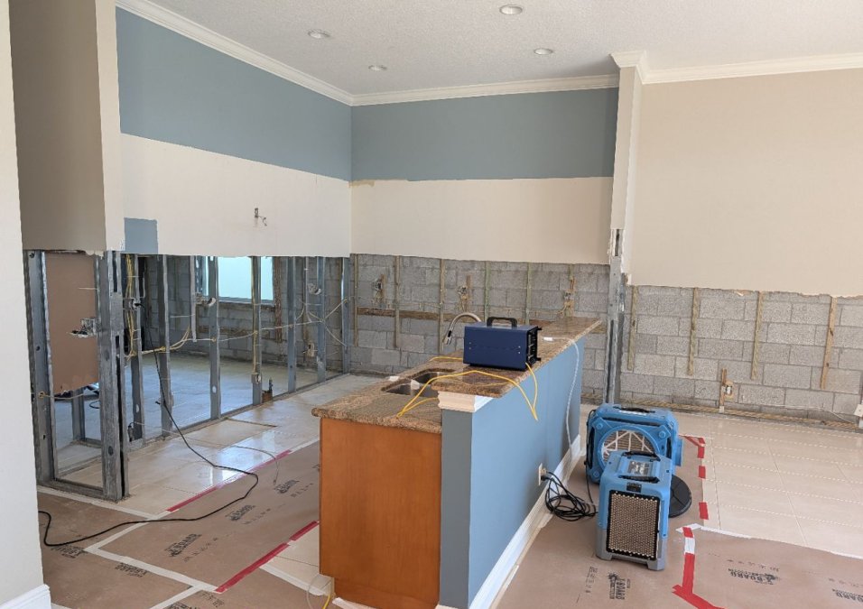 Residential kitchen remediation area with affected cabinetry and wall materials removed and professional JLX equipment in use.