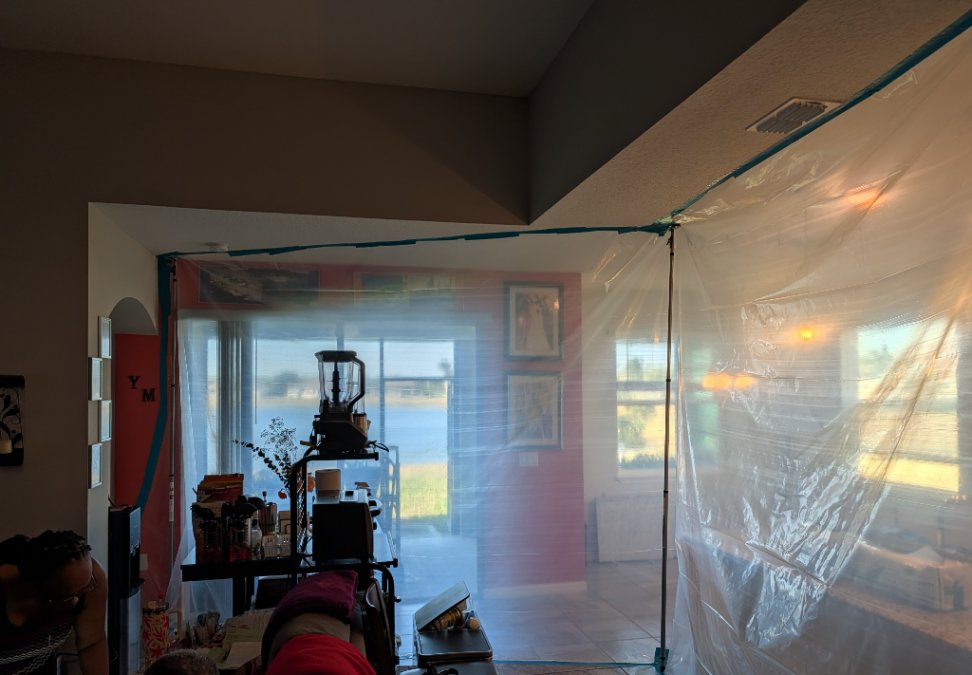 Mold remediation containment separating the work area from the occupied portion of a residential home, with professional equipment inside the containment.