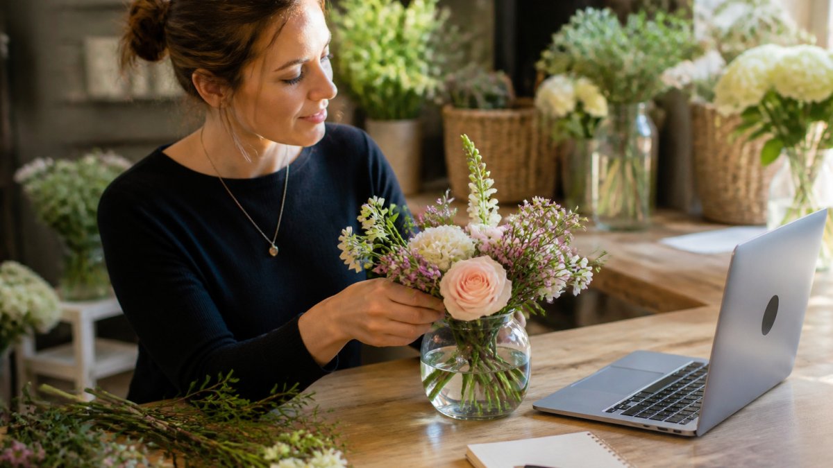 Small bouquet of fresh flowers in a glass vase adding a touch of nature to office desk decor near a laptop