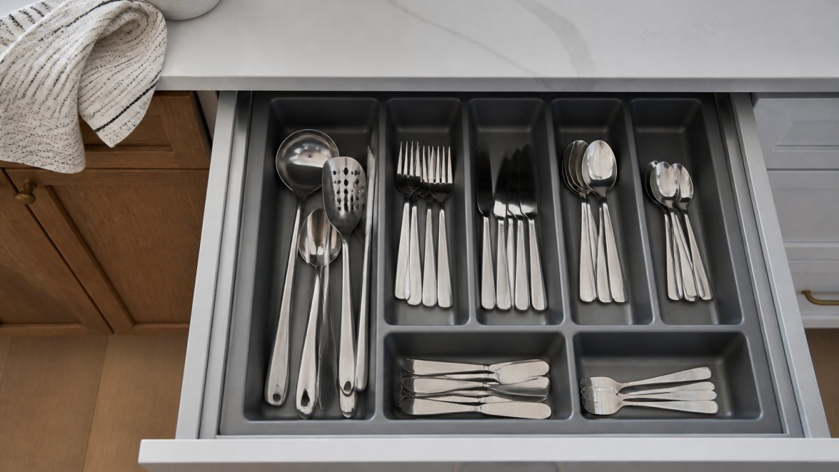 Overhead view of a clean cutlery tray with neatly organized silverware in an open kitchen drawer