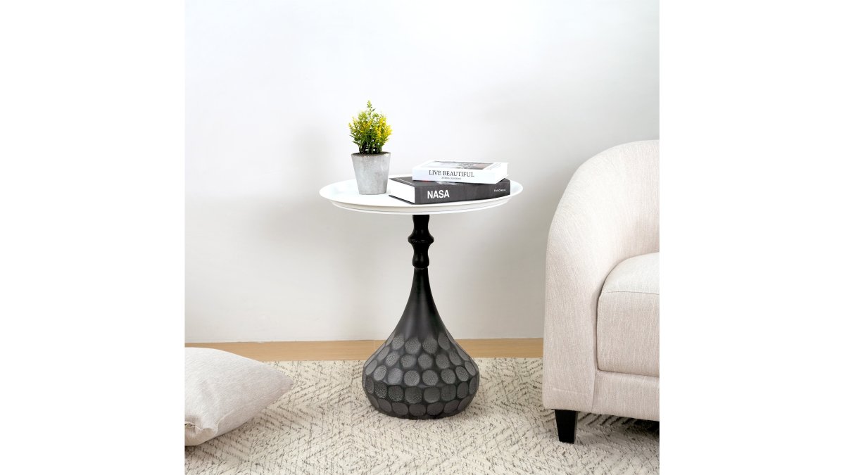 Well-designed living room featuring a modern geometric wall decor piece in gold accents, a hand-hammered metal accent coffee table, a natural jute area rug, canvas wall art with abstract patterns, and decorative vases arranged on surfaces, with warm natural lighting from large windows