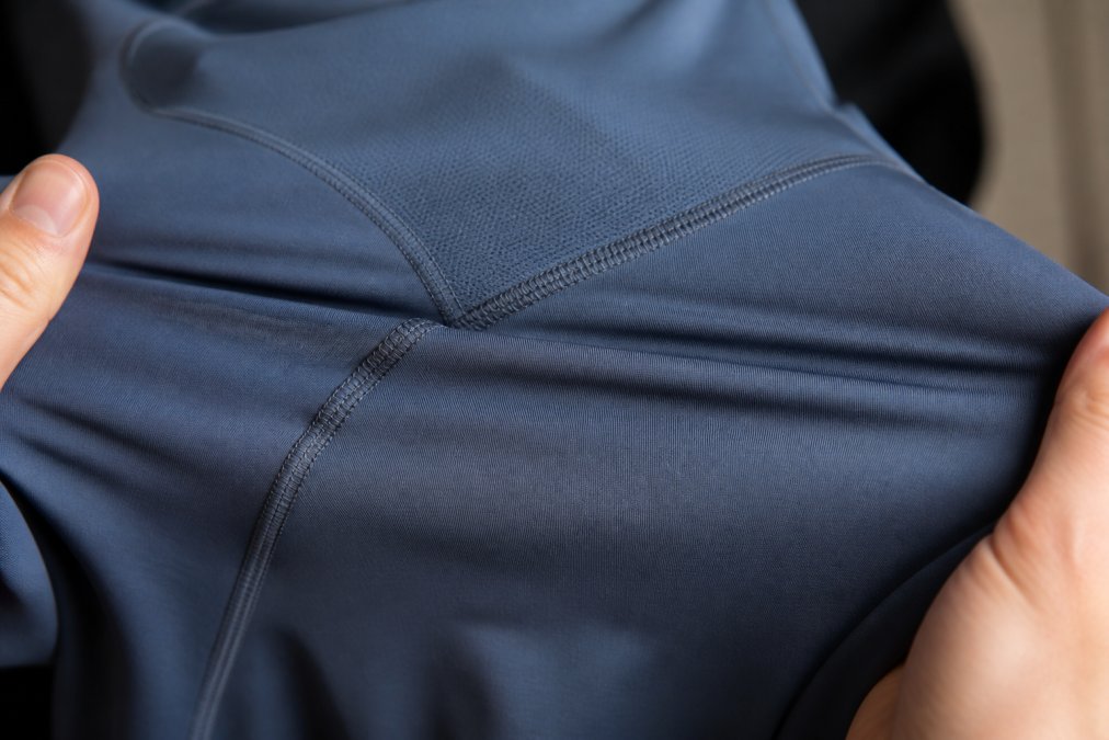 Close-up of premium activewear seams and fabric construction, showing tight stitching, reinforced panels, and four-way stretch material with visible weave quality under natural studio lighting