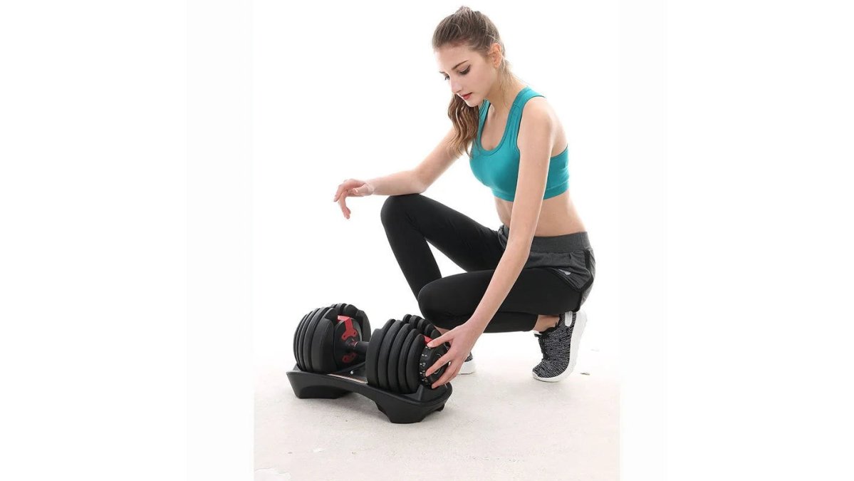 Person performing heavy dumbbell exercise in home gym setting with focused expression, adjustable weights visible on floor, natural window lighting