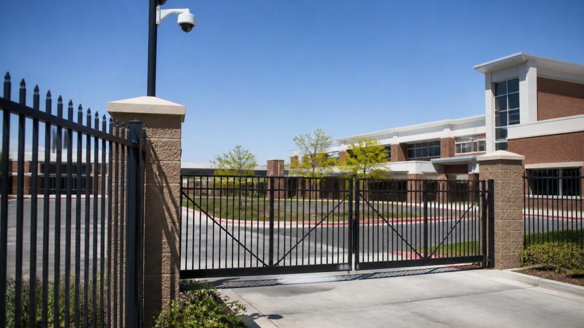 Diagram illustrating layered school perimeter security with fencing, secure gates, and surveillance cameras.